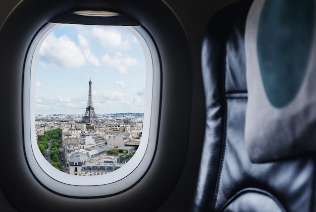 Traveling Paris, France famous landmark and travel destination in Europe. Aerial view Eiffel Tower through airplane window