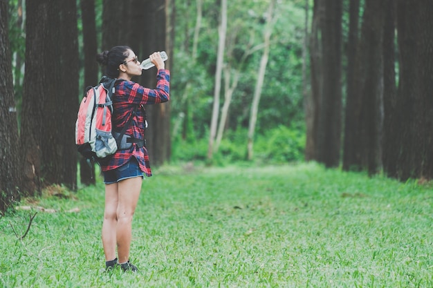 Traveling woman  drinking water after walking in a beautiful nature.