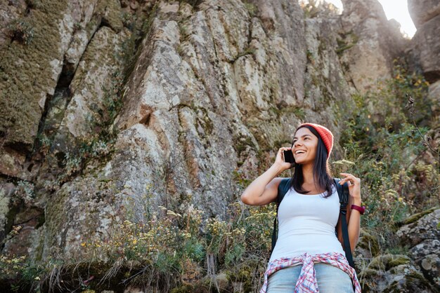 Traveling woman with back backpack talking on phone. from below image