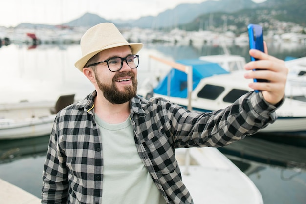 Traveller man taking selfie of luxury yachts marine during sunny day travel and summer concept