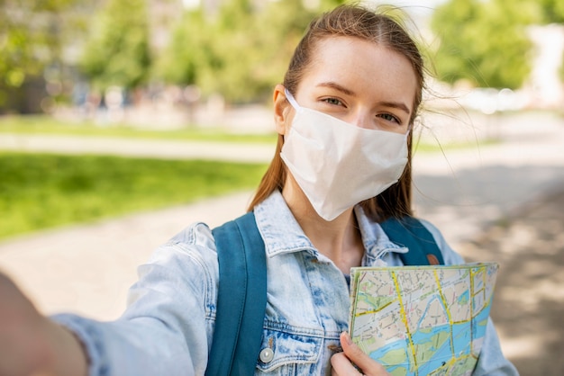 Traveller wearing medical mask and map selfie