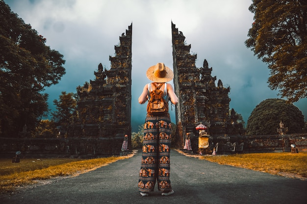 Traveller woman posing in front of a temple in Bali, Indonesia. Woman with backpack on a trip in Asia