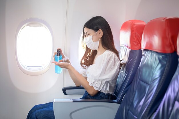 A travelling woman is wearing protective mask is washing hands with alcohol gel onboard