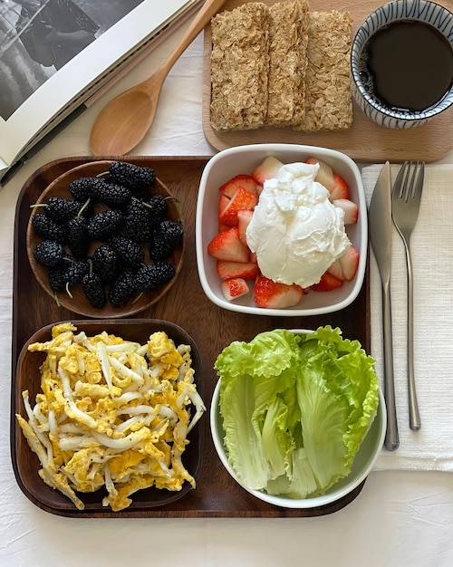 A tray of food including a salad, strawberries, and a bowl of lettuce.