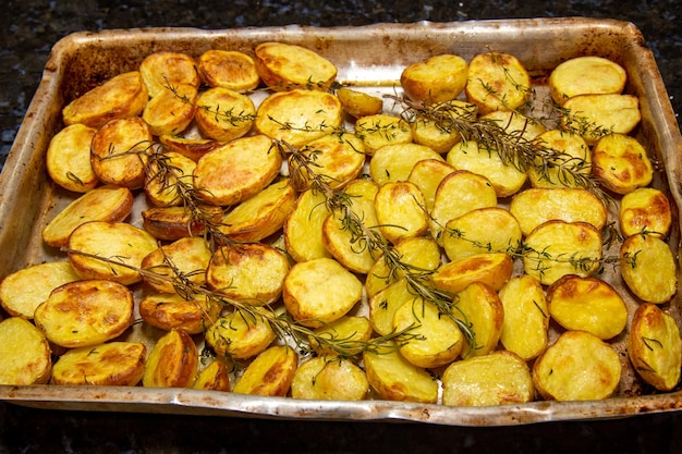 A tray of oven roasted potatoes with rosemary on top.