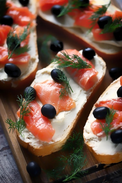 A tray of smoked salmon sandwiches with black olives