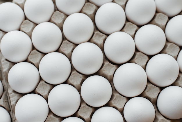 Tray of white fresh eggs close-up on a cardboard form. Agricultural industry.