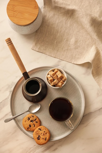 Tray with glass cup of coffee sugar cookies and turkish pot on white marble table flat lay