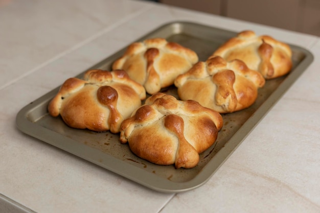 Tray with pan de muerto freshly baked on the counter of a Mexican kitchen