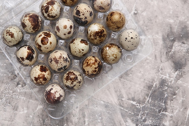 Tray with quail eggs on gray concrete background Top view