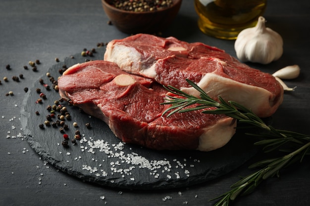 Tray with steak meat with herbs and spices on dark wooden table