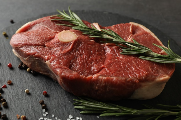 Tray with steak meat with herbs and spices on dark wooden