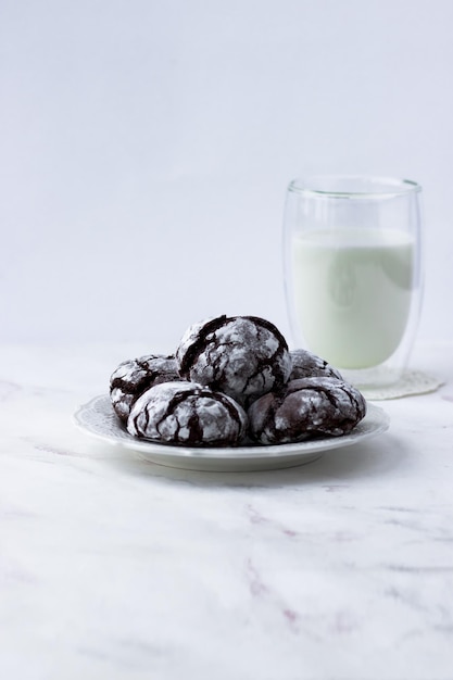 Treats on a white table Chocolate cracks cookies and a glass of milk