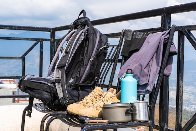 Trecking or hiking equipment - bagpack, boots, socks, pants, folding knife, water flask, kettle pot and flashlight. Outdoor activity concept. Still life close up stock photo.