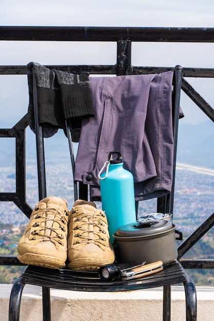 Trecking or hiking equipment - boots, socks, pants, folding knife, water flask, kettle pot and flashlight. Outdoor activity concept. Still life close up stock photo.