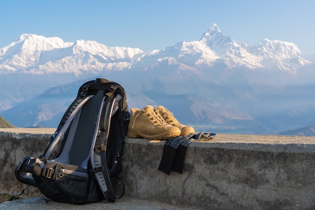 Trecking or hiking equipment set with Annapurna mountain range on background. Bagpack, hiking shoes and socks. Outdoor activity concept.