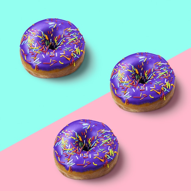 Tree donut with violet glaze and icing on pink and blue background Fashion minimalism style Flat lay