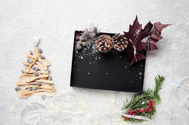 Tree made with wooden spoons as Christmas decoration Black box with pine cones and branches