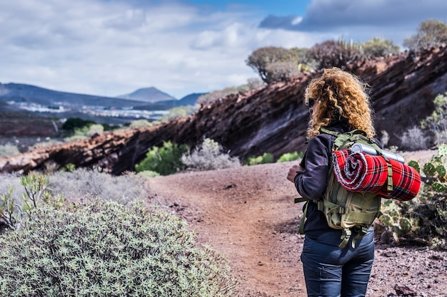 Trekking woman in outdoor leisure activity with backpack enjoying the nature and the mountain - alternative travel and vacation concept - enjoying earth and her beauty - back view