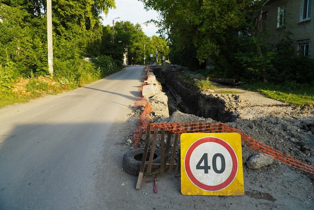 Trench in the asphalt along the street for laying the pipeline Fenced construction work