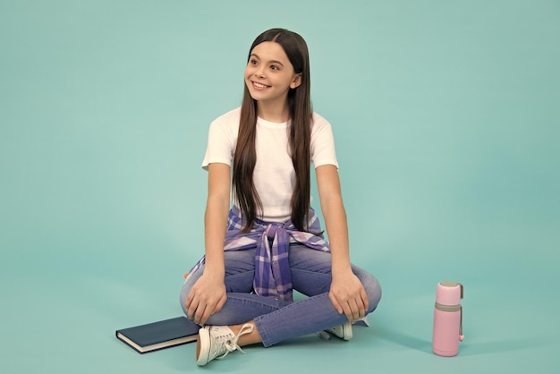 Trendy beautiful teenage model posing on blue studio background Child girl in tshirt and jeans Studio shot Teen fashion Happy teenager positive and smiling emotions of teen girl