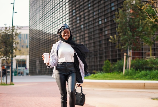 Trendy black woman with takeaway coffee rushing on work