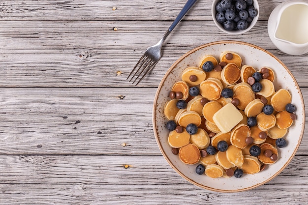 Trendy breakfast with mini pancakes, blueberries and chocolate chips, top view.