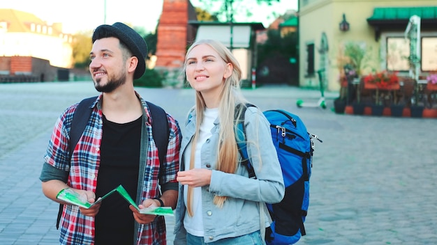 Trendy couple of tourists finding necessary destination on map and admiring surroundings