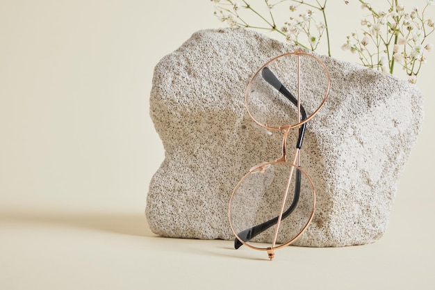 Trendy fashion eyeglasses on concrete podium and Gypsophila flowers on beige background