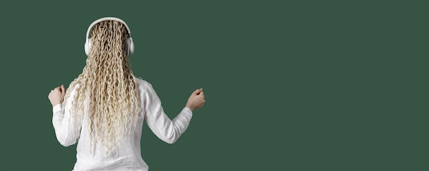 Trendy female wearing white shirt in headphones on head listening to music dancing enjoy