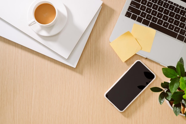 Trendy feminine home office workspace. White office desk. Laptop, coffee cup and phone, notebook, pencil. Flat lay, top view, copy space