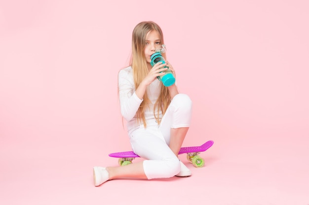 Trendy girl Girl having fun with penny board pink background Kid adorable child long hair adore ride penny board Ride penny board and do tricks Girl likes to ride skateboard Active lifestyle