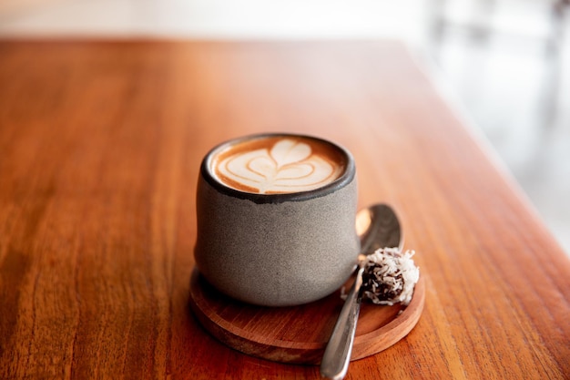 Trendy grey stylish cup of hot cappuccino with latte art on wooden table background One cup for morning routine