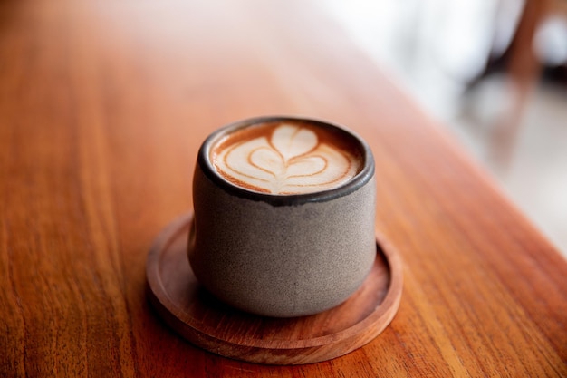 Trendy grey stylish cup of hot cappuccino with latte art on wooden table background One cup for morning routine