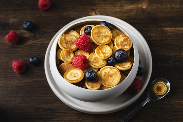 Trendy homemade breakfast, pancake cereal, mini pancakes with berries,