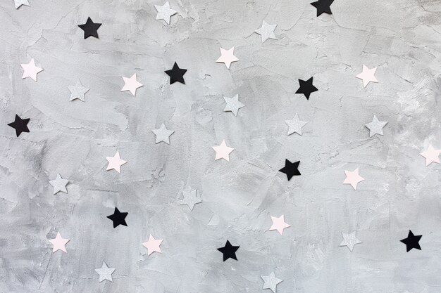 Trendy paper confetti stars on gray background. 