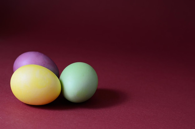 Trendy photo of Three multi colored easter eggs on a dark purple background.