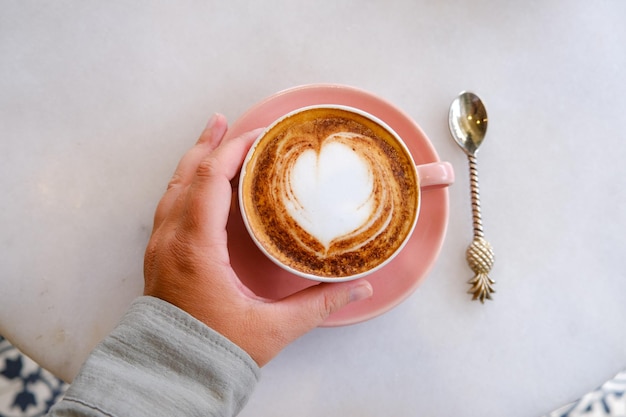 Trendy pink cup of hot cappuccino on marble table background