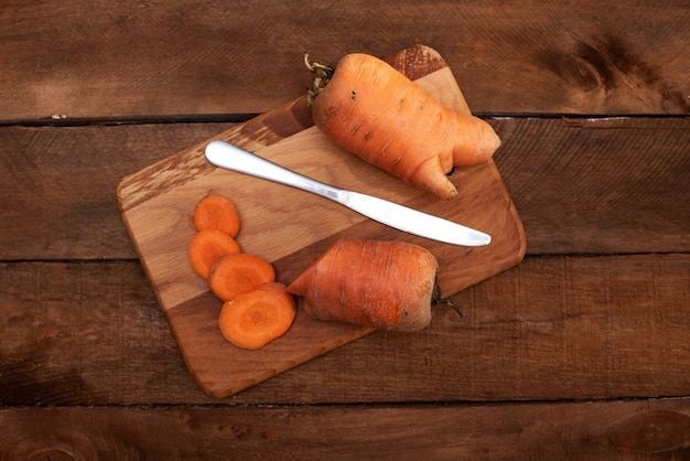 Trendy ugly organic carrot from home garden bed on barn wood table, Australian grown. Color-toning effect applied.