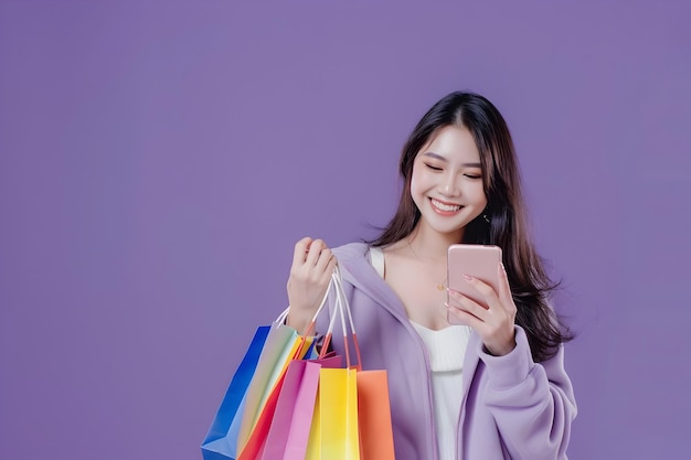 Trendy Young Asian Woman Carrying Colorful Bags Shopping Online with Mobile Phone on Purple