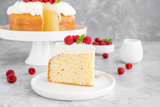 Tres leches cake with whipped cream and fresh raspberries on top of a gray concrete background