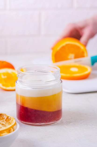 Tri-color jelly - white (coconut), orange (orange), red (strawberry). Homemade desserts with gelatin (collagen), healthy food. Jelly in a jar