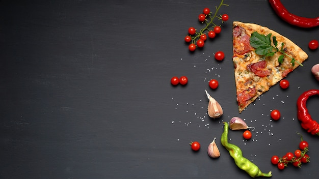 Triangular piece of baked pizza with mushrooms, smoked sausages, tomatoes and cheese