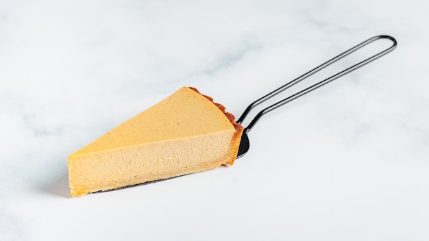 Triangular piece of a fresh tasty vegan cake on a cake server isolated on a white background