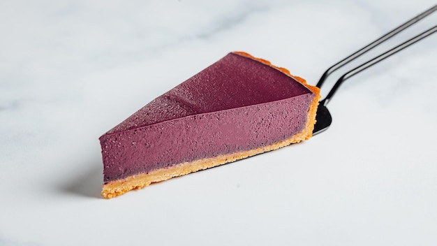 Triangular piece of a fresh tasty vegan cake on a cake server isolated on a white background