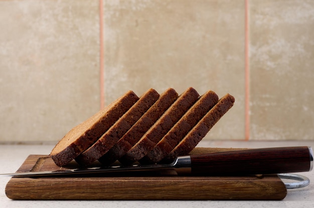 Triangular rye piece of bread on a wooden cutting board