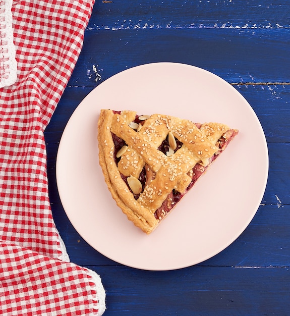 Photo triangular slice of baked cherry pie on a pink round plate