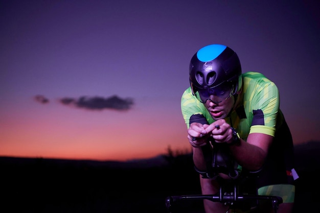 triathlon athlete riding bike fast at night