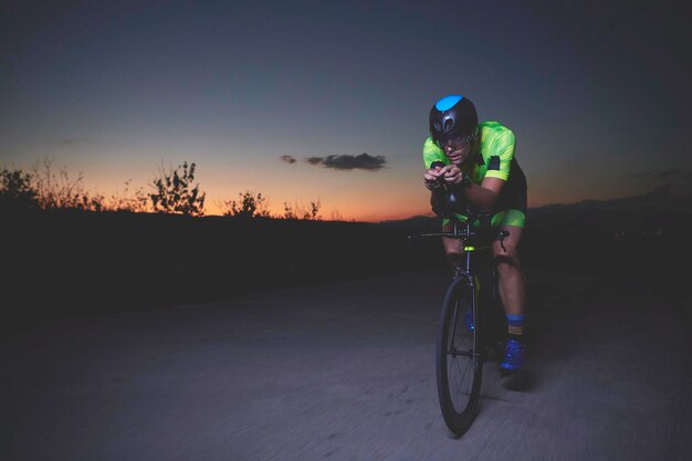 Photo triathlon athlete riding bike fast at night