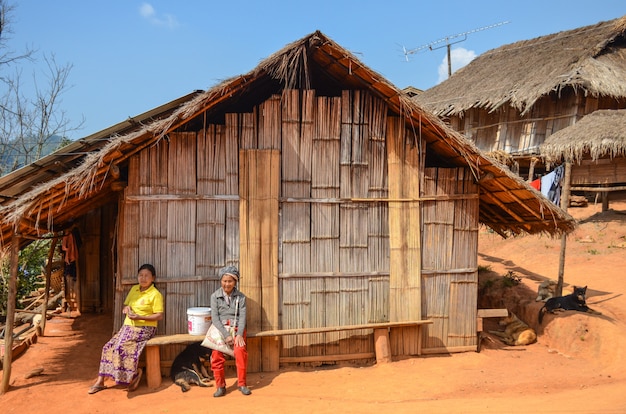 Tribal woman sitting in front of their home